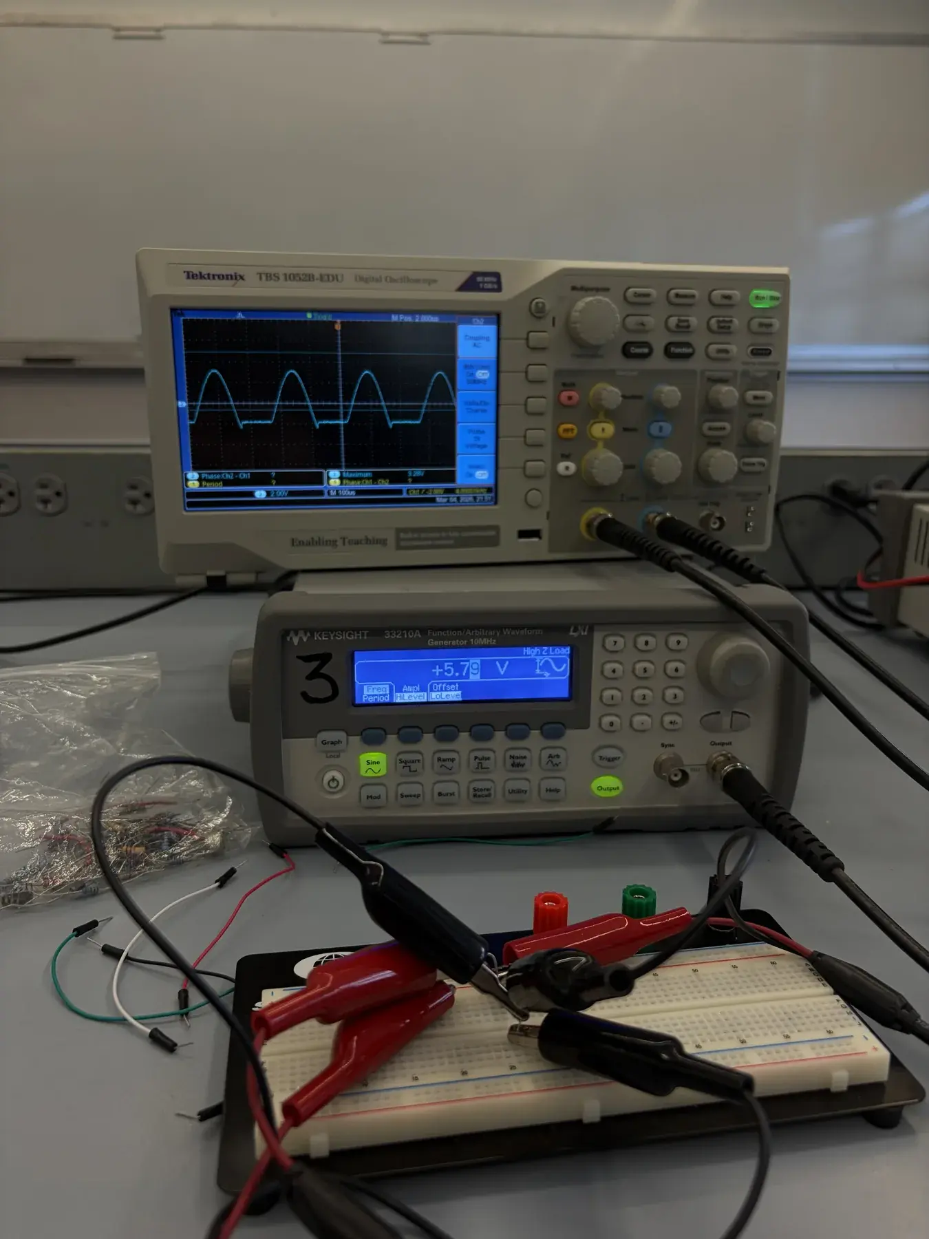 Lab bench with a Tektronix oscilloscope, Keysight function generator, probes, leads, and a breadboard