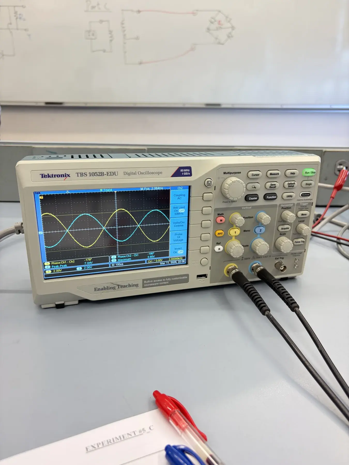 Oscilloscope displaying two sinusoidal traces with visible phase measurements